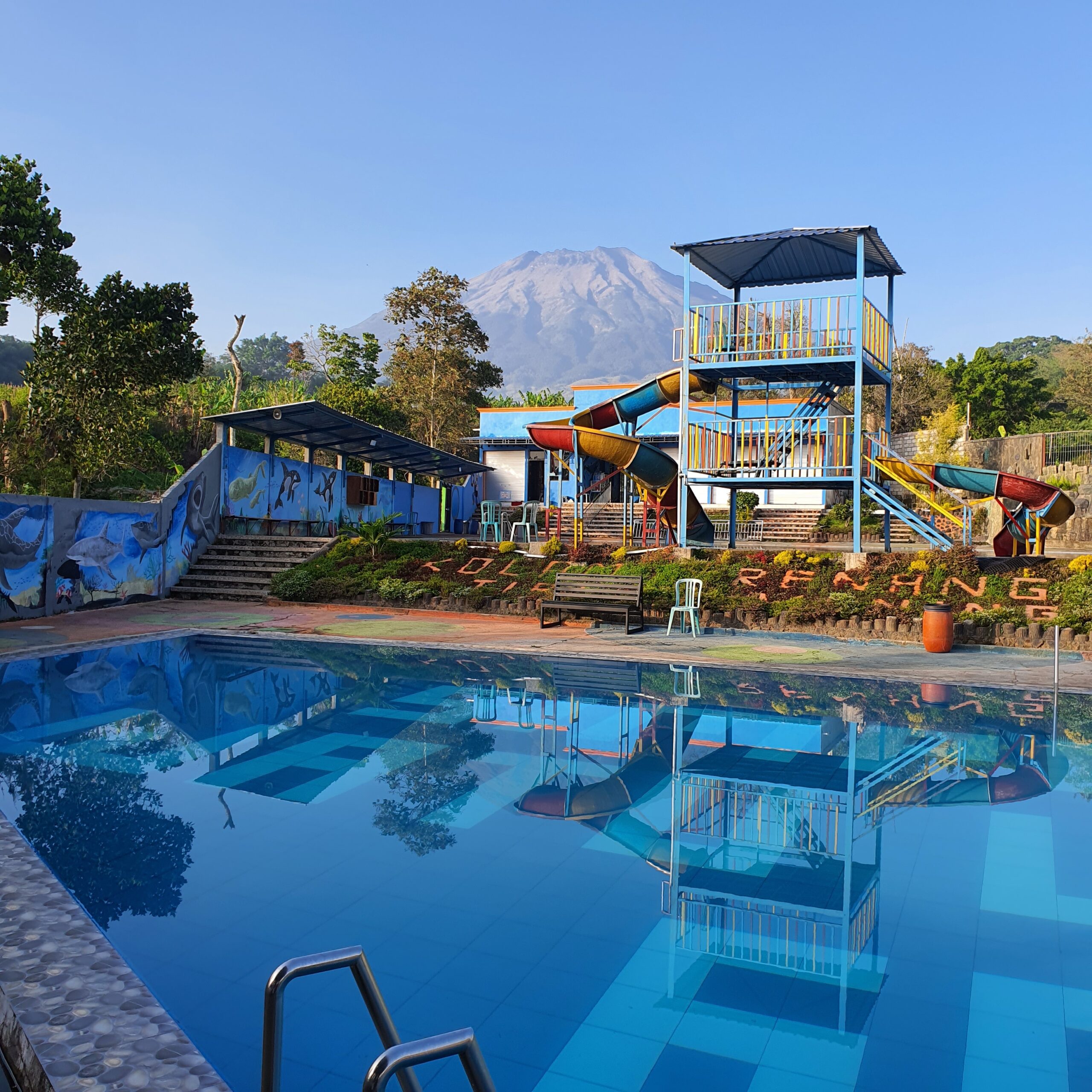 a large blue swimming pool with a slide in the background
