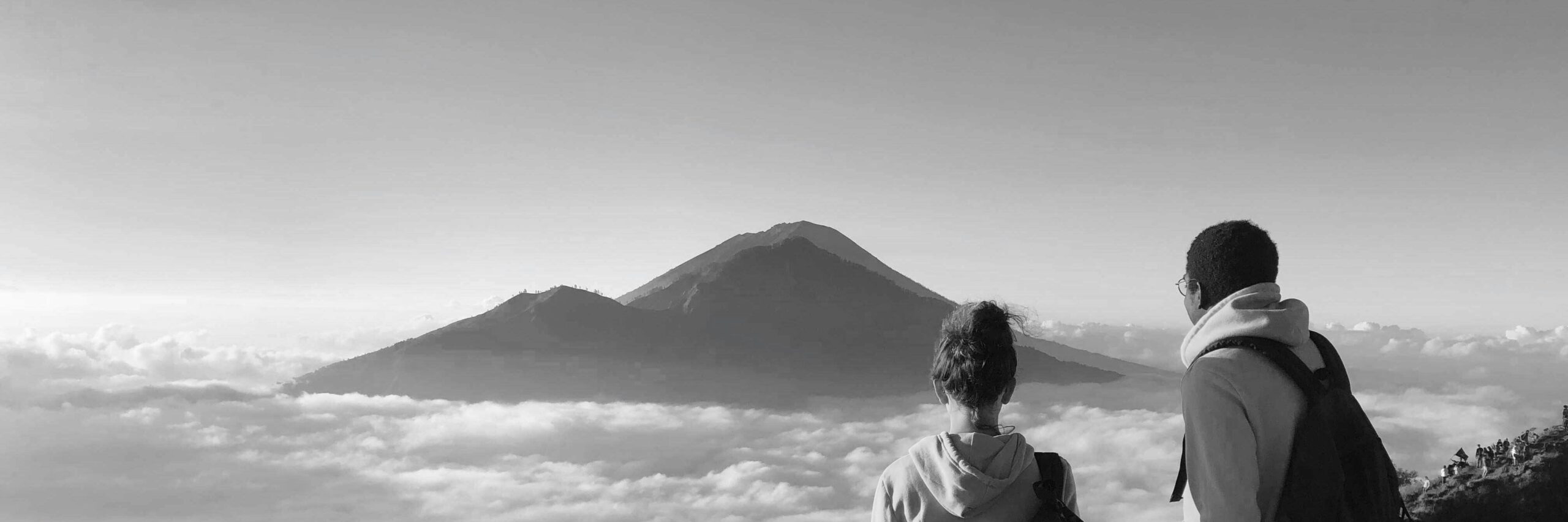 grayscale photo of man in white shirt looking at mountain